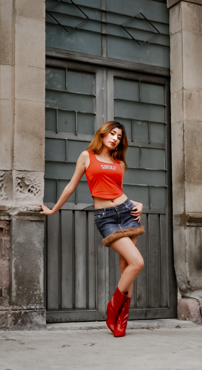 Stylish woman in red boots posing against vintage architecture background.