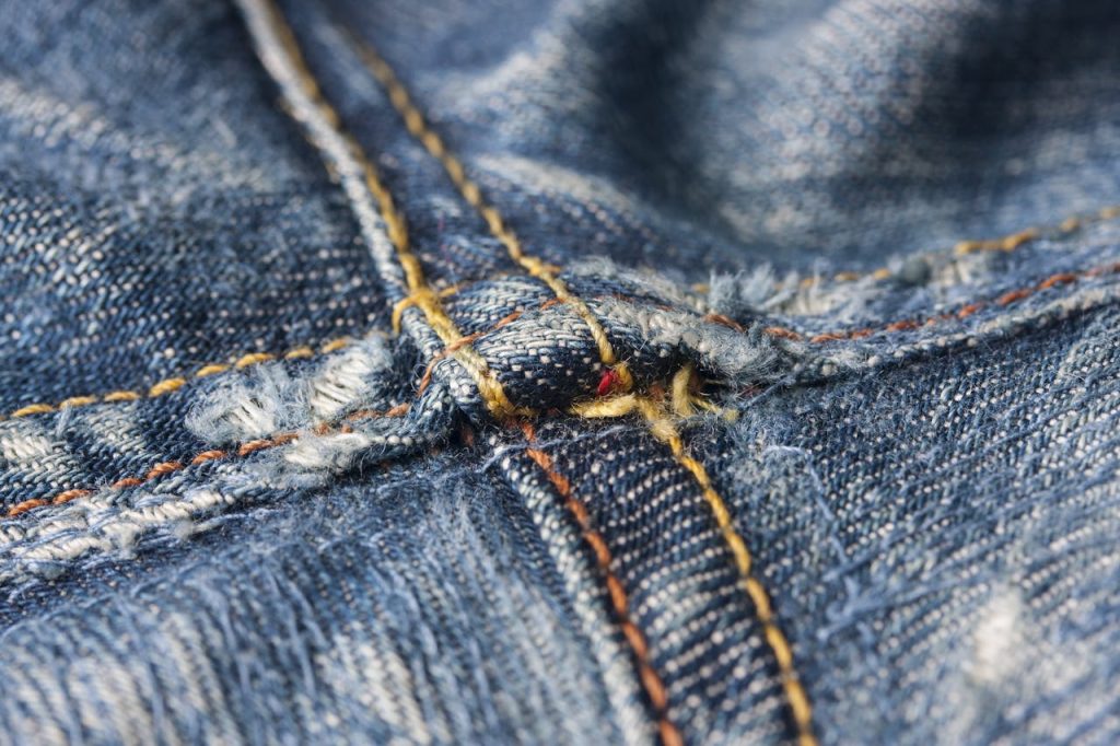 Macro image highlighting the intricate stitching details of denim jeans fabric.